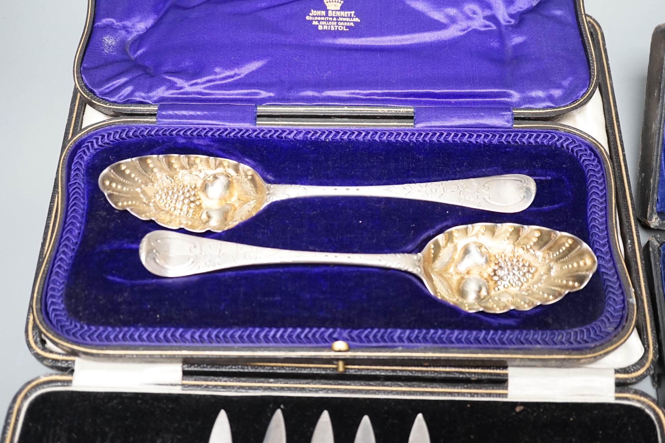 Two 18th century silver 'berry' spoons in associated case and three other cased sets including, pair of silver mounted glass knife rests, a cased set of six seal top coffee spoons and a part set of dessert eaters.